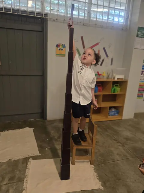 Niño construyendo una torre alta con la escalera marrón Montessori