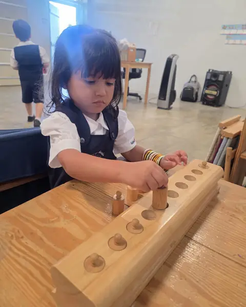 Niña trabajando con los cilindros encajables Montessori