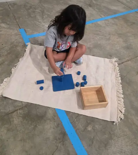 Niña trabajando con los cilindros azules sobre la alfombra