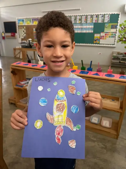 Niño mostrando su cohete espacial terminado