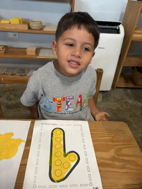 Niño mostrando su letra completa estampada con esponja