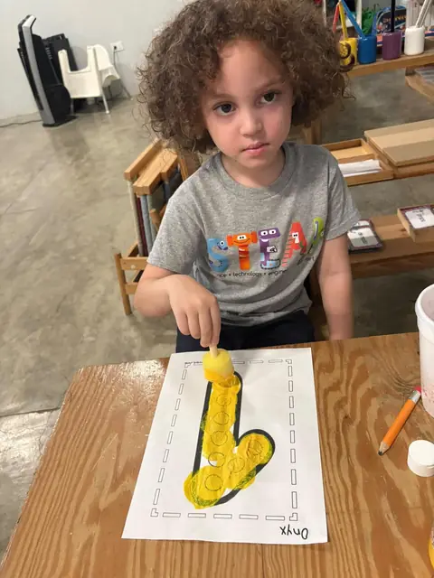 Niña estampando con esponja el contorno de su letra