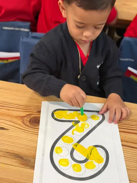 Niño estampando con esponja el número siete en amarillo
