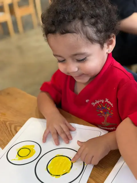 Niña señalando los círculos que pintó de amarillo