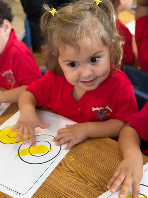 Niña sonriente pintando círculos con los dedos
