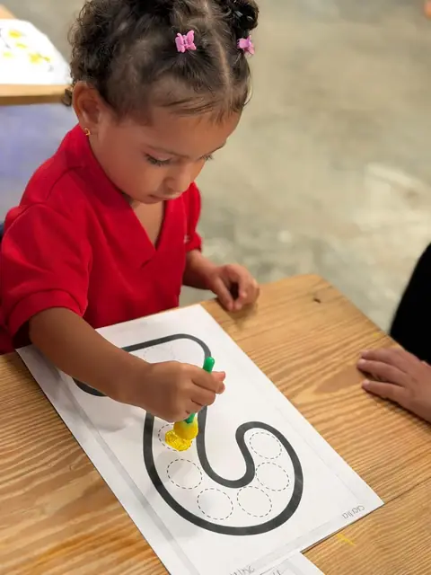 Niña trazando con esponja amarilla la letra de su lámina