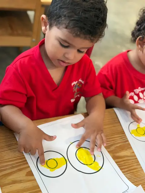 Niños pintando círculos de amarillo con los dedos