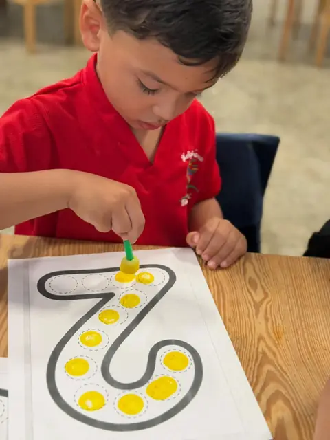 Niño completando con esponja los puntos del número siete