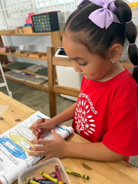 Niña coloreando crayolas de colores en su libro de actividades