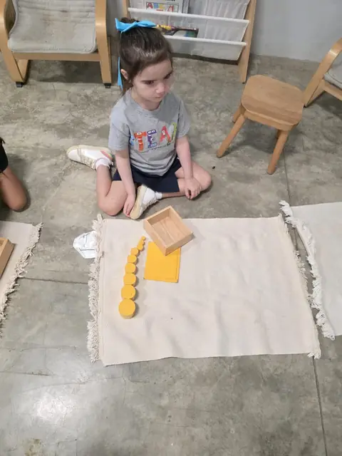 Niña trabajando los cilindros amarillos sobre su alfombra