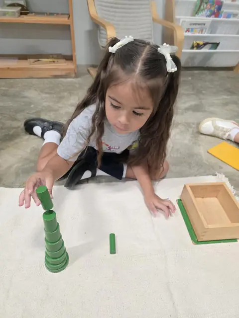Niña construyendo la torre de cilindros verdes