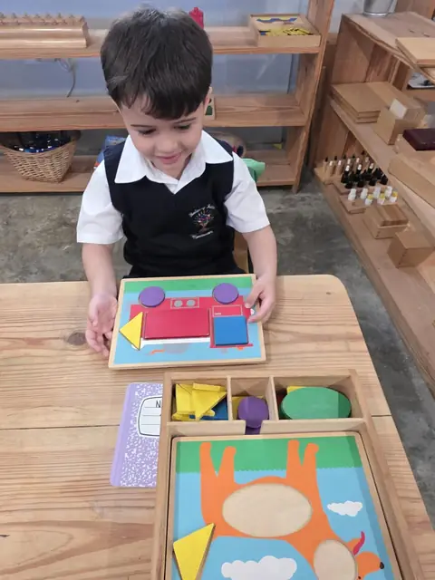 Niño sonriente completando rompecabezas de figuras geométricas