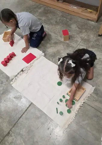 Dos niñas trabajando los cilindros de colores en sus alfombras