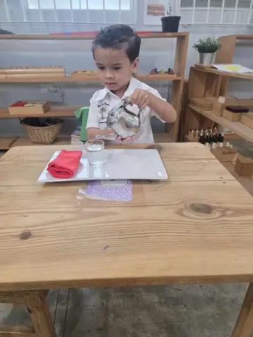 Niño practicando vida práctica sirviendo agua en su vaso