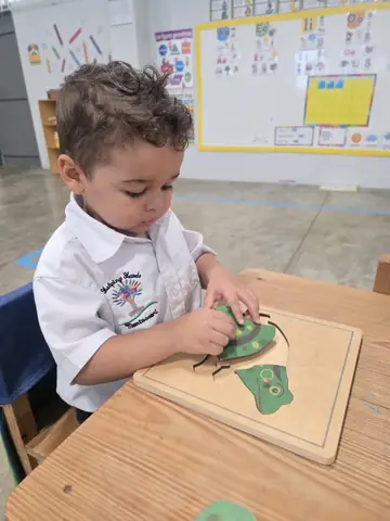 Niño armando el rompecabezas de la rana en su mesa