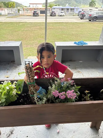 Niña cuidando las plantas del jardín con sus guantes