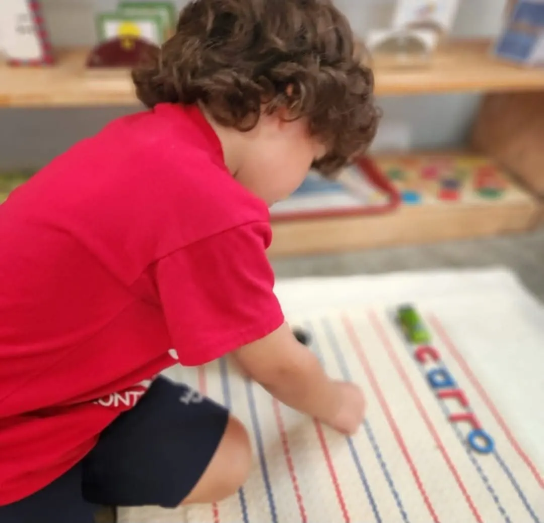 Niño trabajando letras sobre una alfombra Montessori