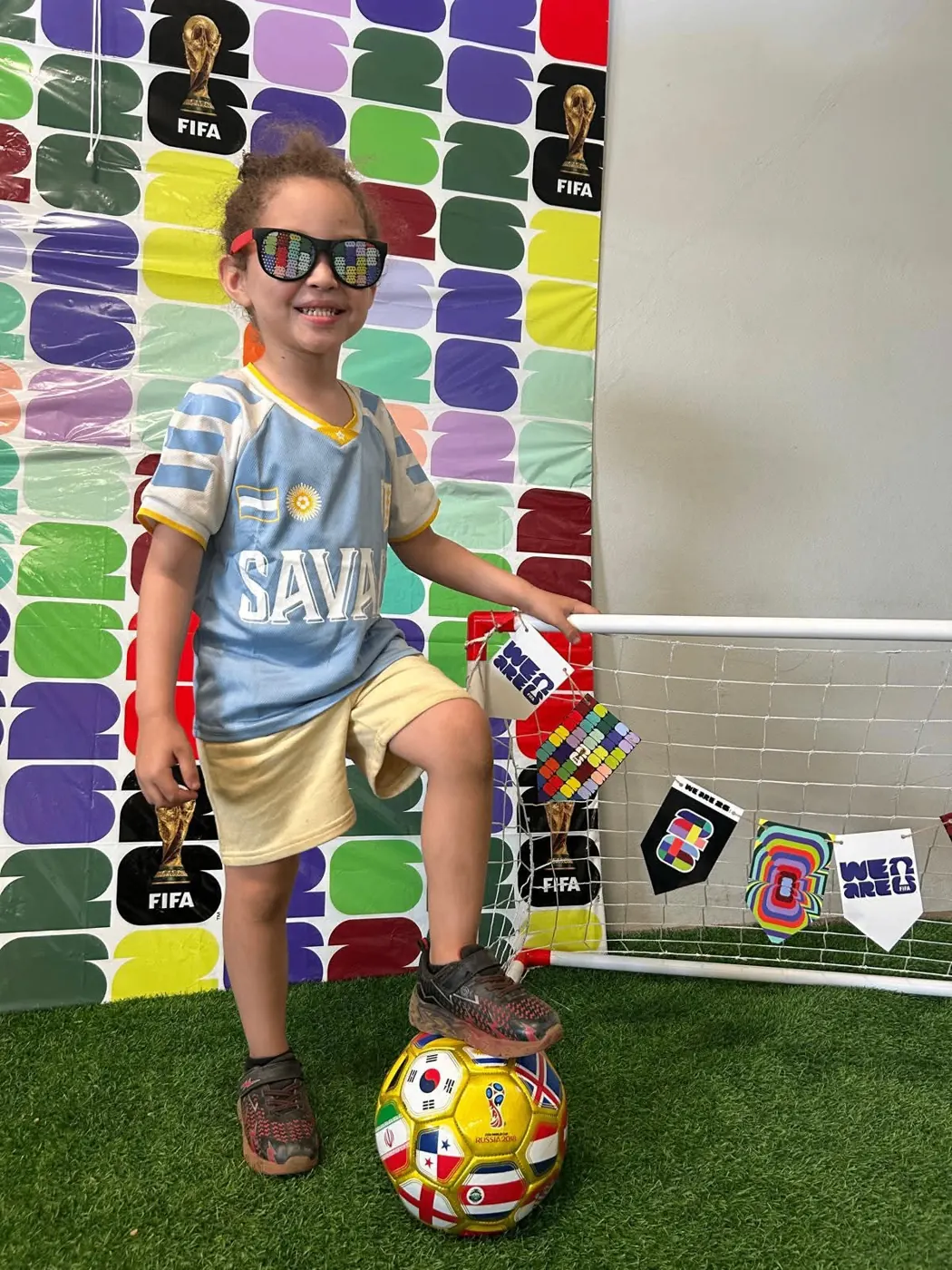Niña con camiseta de fútbol posando con balón en el evento World Cup