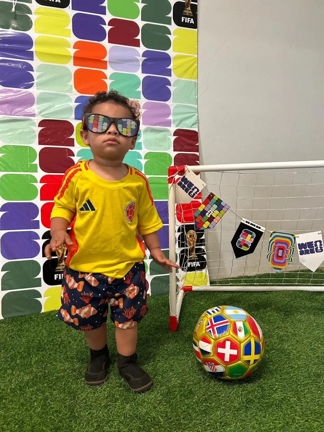 Niño con uniforme amarillo posando junto al balón mundialista