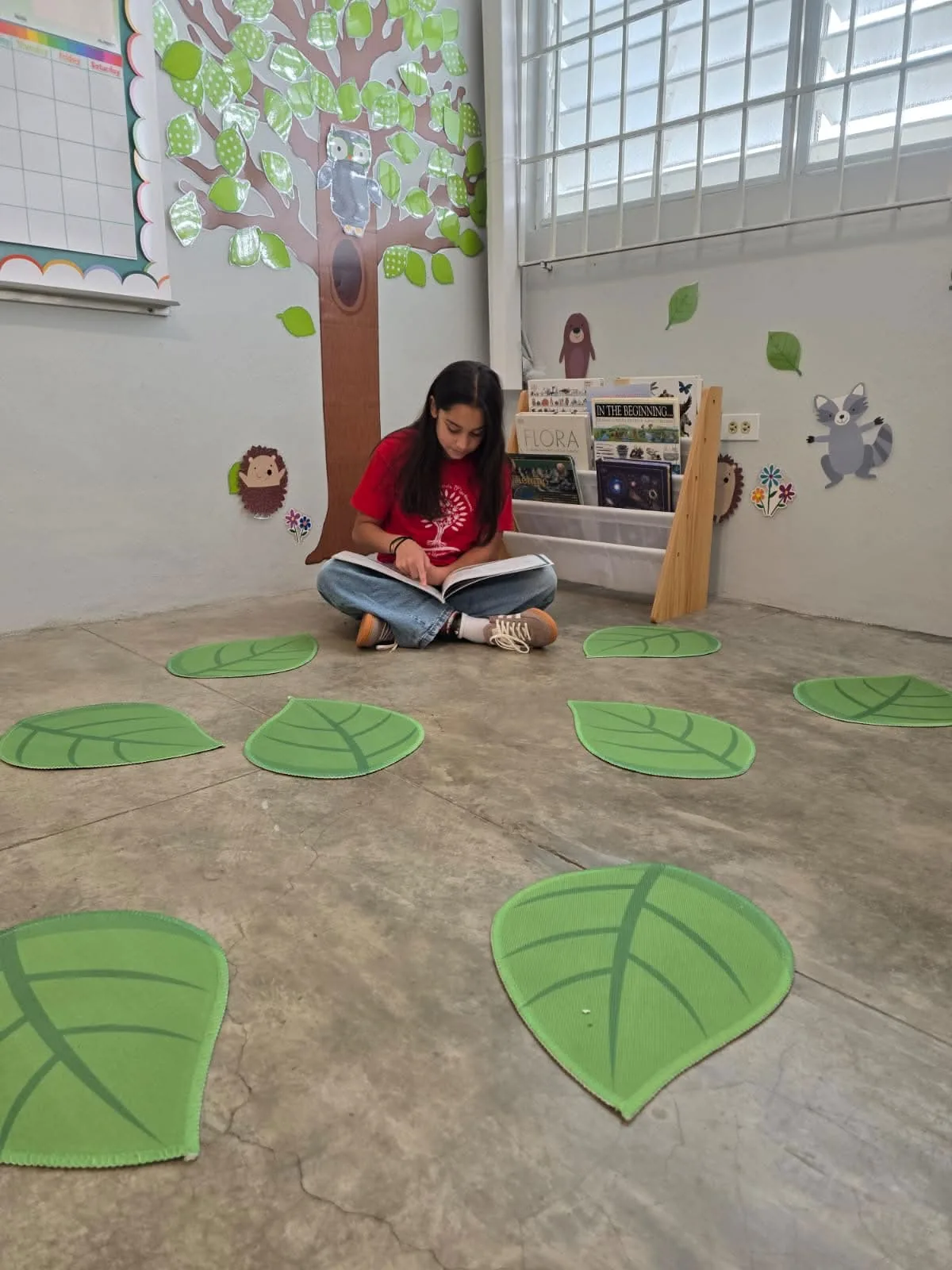 Estudiante leyendo en el rincón de lectura con árbol decorativo