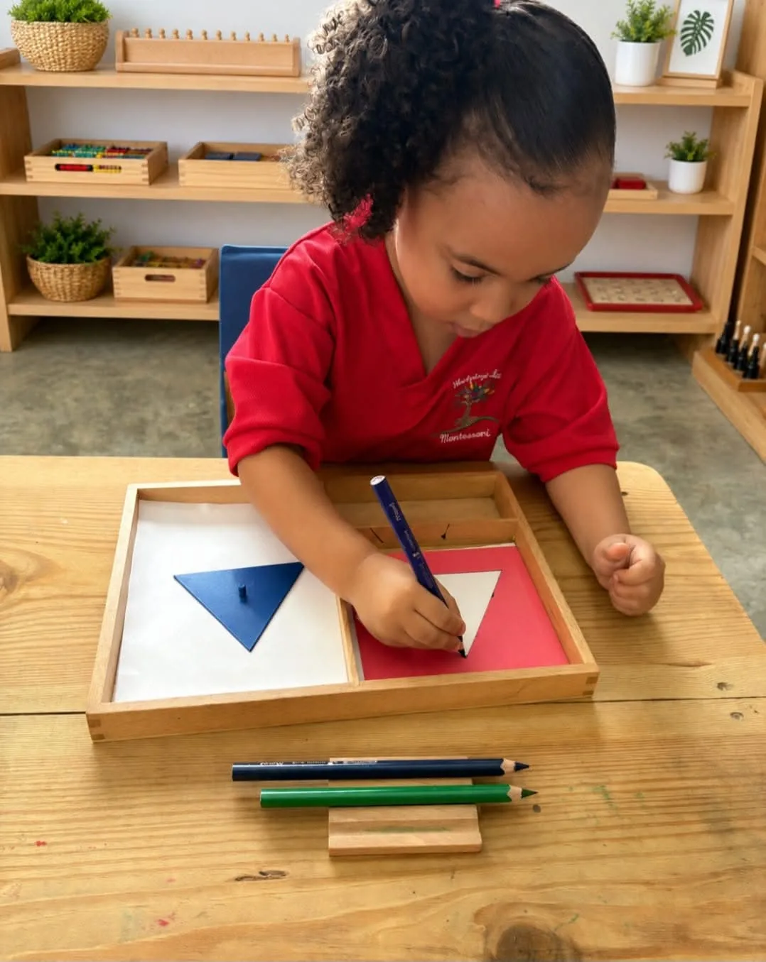 Niña calcando figuras geométricas con lápices de colores